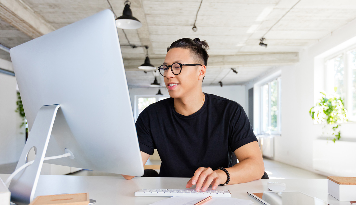 An Online MS in Computer Science student works at a desktop computer in an airy, light-filled office.
